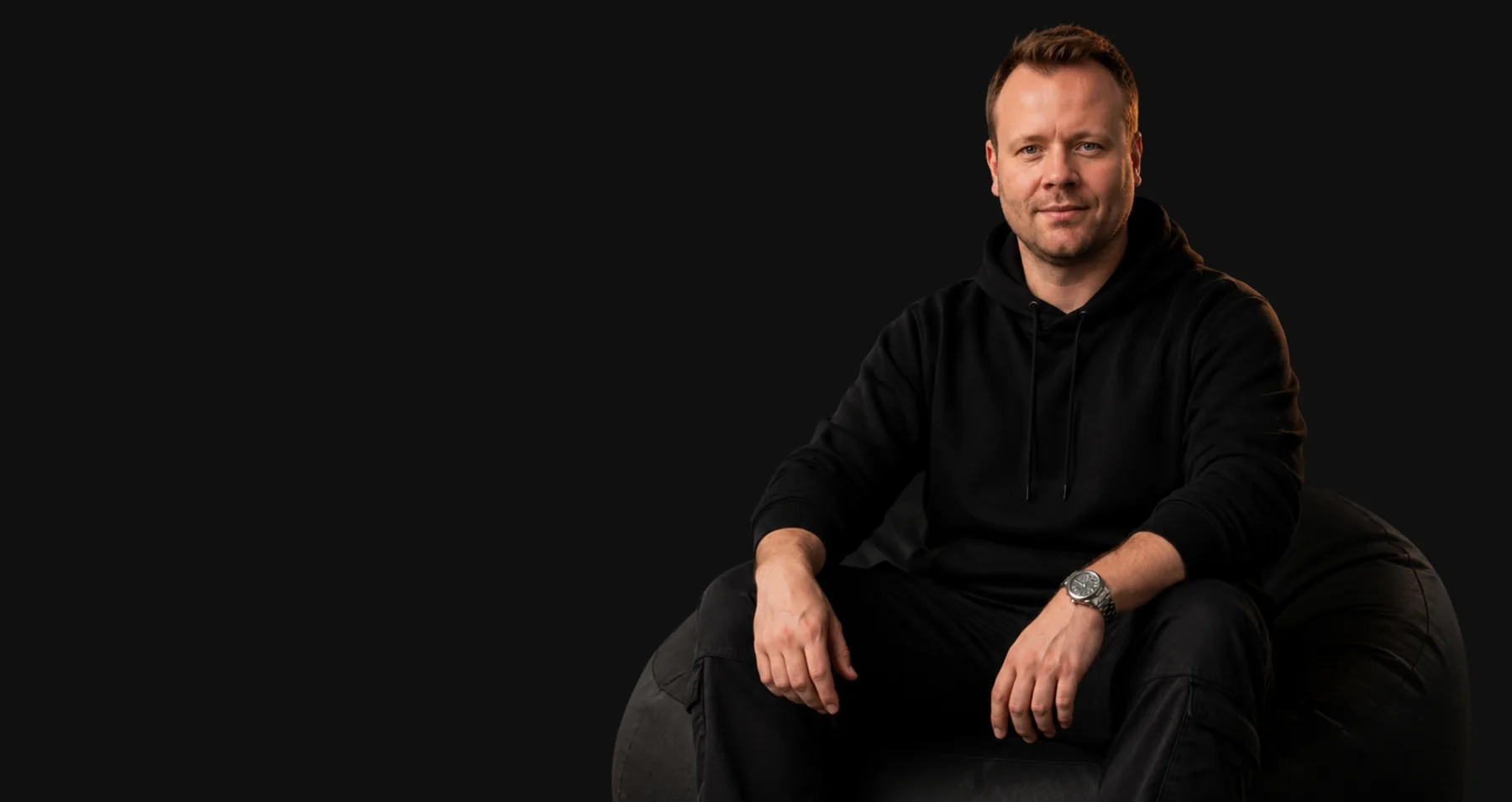 Palski, sitting on a black beanbag against a dark backdrop